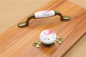 Detail of vintage bronze furniture handles with hand-painted floral ceramic accents