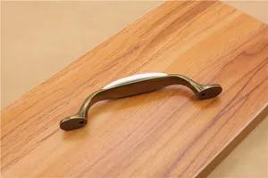Detail of vintage ceramic drawer handle with bronze metal base on wooden surface