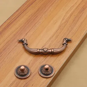 Antique red copper drawer handle set with ornate classical patterns on wooden background