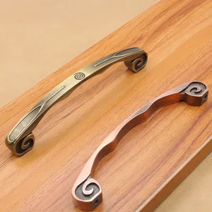 Close-up of antique bronze zinc alloy cabinet handles on a textured wooden surface