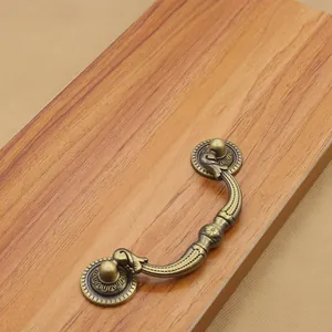 Macro detail of antique bronze cabinet handle with floral carvings on wood background