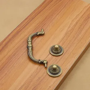Detailed close-up of antique bronze furniture handle set on a natural wood surface