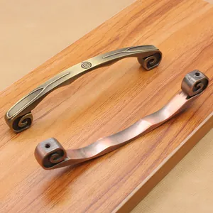 Detail of antique zinc alloy handles in bronze and red copper with European scroll patterns
