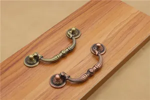 Close-up of antique bronze furniture handles with ornate European carvings on wood