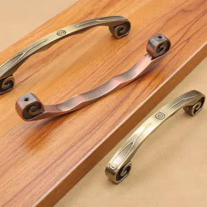 Macro detail of antique bronze drawer handles with ornate spiral engraving and brushed texture