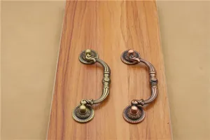 Detailed close-up of antique bronze and copper drawer handles with ornate floral patterns
