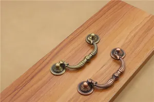 Detail of antique bronze drawer pulls with classic embossed patterns on wood