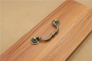 Close-up of antique bronze furniture handle with embossed patterns on wood