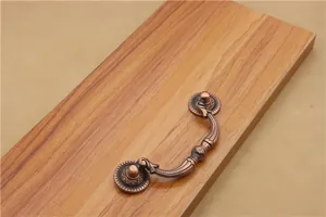 Macro view of antique bronze cabinet pull handle with ornate floral carving details