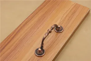 Detail view of vintage red bronze drawer handle with embossed patterns on wood