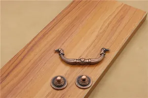 Macro detail of antique bronze drawer handle with ornate geometric patterns on wood
