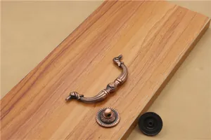 Detailed view of antique bronze furniture handle and ornate bases on wood grain surface