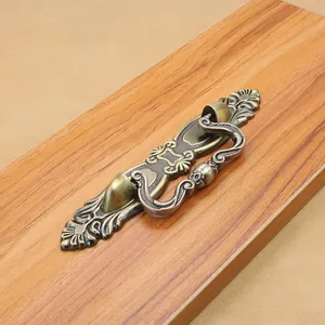 Detail of vintage antique bronze drawer pull with ornate floral engraving on wood