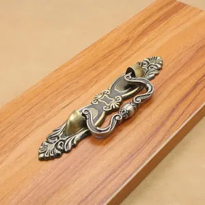 Close-up of vintage bronze zinc alloy furniture handle with floral carving on wood