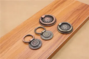 Macro shot of antique zinc alloy drawer pull rings with flower embossed base on wood