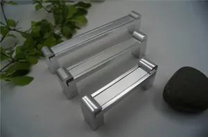Drei Größen silberner matter Aluminium-Möbelgriffe auf einer texturierten weißen Fläche