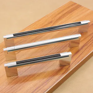 Detail view of modern black and silver furniture handles in three sizes on wood surface