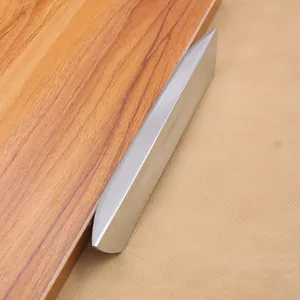 Macro shot of a modern silver alloy cabinet handle with a brushed matte finish on wood