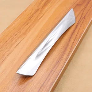 Close-up of modern silver chrome drawer handle with marble texture on wood surface