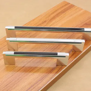 Three sleek black U-shaped aluminum cabinet handles displayed on a wooden board