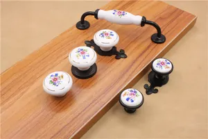 Detail of floral ceramic drawer knobs and pulls with black metal base on wood surface