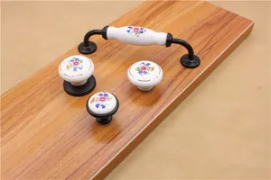 Close-up of white ceramic cabinet knobs and pulls with purple and blue flower patterns