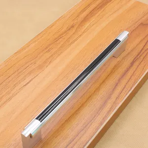 Detail of silver aluminum U-shaped cabinet pull handle with black inlay on wood