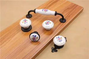 Floral ceramic cabinet handle with black base on wooden surface for furniture