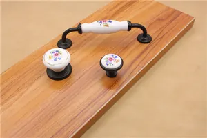 Close-up of ceramic cabinet handles with colorful floral patterns and black metal bases