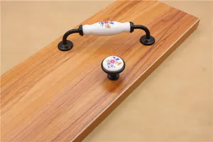 Detail of floral ceramic cabinet handles with black metal bases on a wooden board