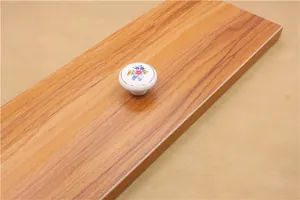 Macro detail of white ceramic drawer knob with floral pattern and golden edge finish