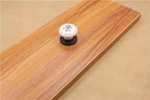 Detail of floral ceramic drawer knob with white glaze and black base on wood surface