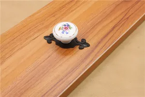 Detailed view of floral ceramic cabinet knob with vintage black metal filigree base