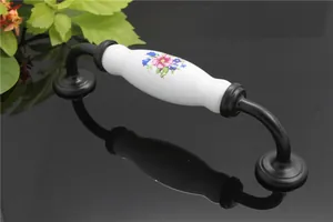 Close-up of floral pattern ceramic cabinet handle with black metal base and screws