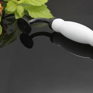 Close-up of ceramic and black metal cabinet handle featuring vintage minimalist design