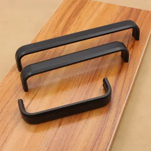 Tre maniglie per mobili a forma di U in alluminio nero opaco di diverse lunghezze su legno