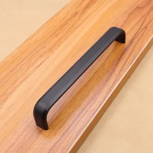 Dettaglio macro della maniglia nera opaca a forma di U per mobili su superficie in legno