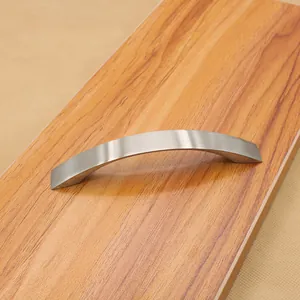Close-up of modern silver curved cabinet handle on wooden surface with brushed finish