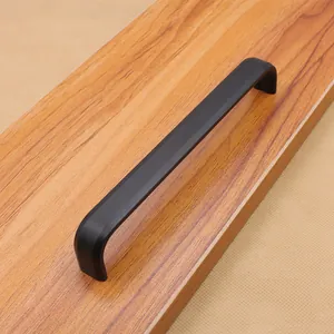 Dettaglio macro di una moderna maniglia a U nera opaca per mobili su venatura del legno naturale