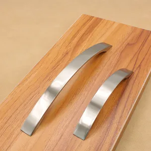Modern brushed aluminum cabinet handles with curved ergonomic design on wooden board