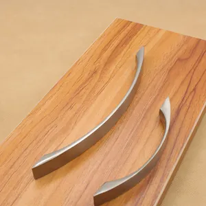 Close-up of brushed silver aluminum handles with curved design on wooden texture surface