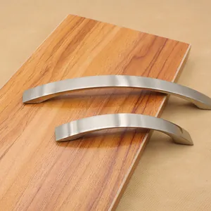 Detail of brushed aluminum curved furniture handles on a modern wooden surface