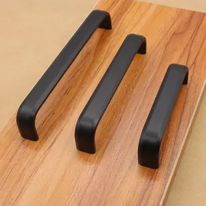 Tre maniglie per mobili a U nero opaco con bordi arrotondati su fondo legno