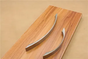 Close-up of curved brushed aluminum cabinet handles in two sizes on wood surface