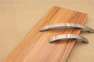 Close-up of curved brushed silver aluminum cabinet handles in two sizes on wood