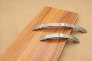 Close-up of brushed aluminum curved cabinet handles in two sizes on wooden background