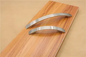 Detailed macro of curved brushed silver aluminum cabinet handles on a wood surface