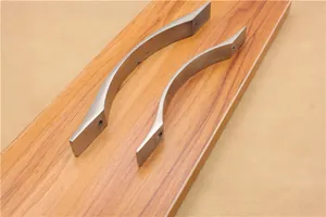 Dettaglio di maniglie per mobili in alluminio spazzolato con design curvo su superficie in legno