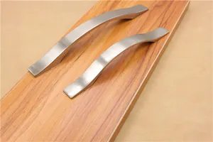 Dettaglio delle maniglie in argento spazzolato a forma di onda su fondo di legno