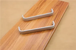 Macro detail of matte silver aluminum U-shaped cabinet handles on a wooden surface
